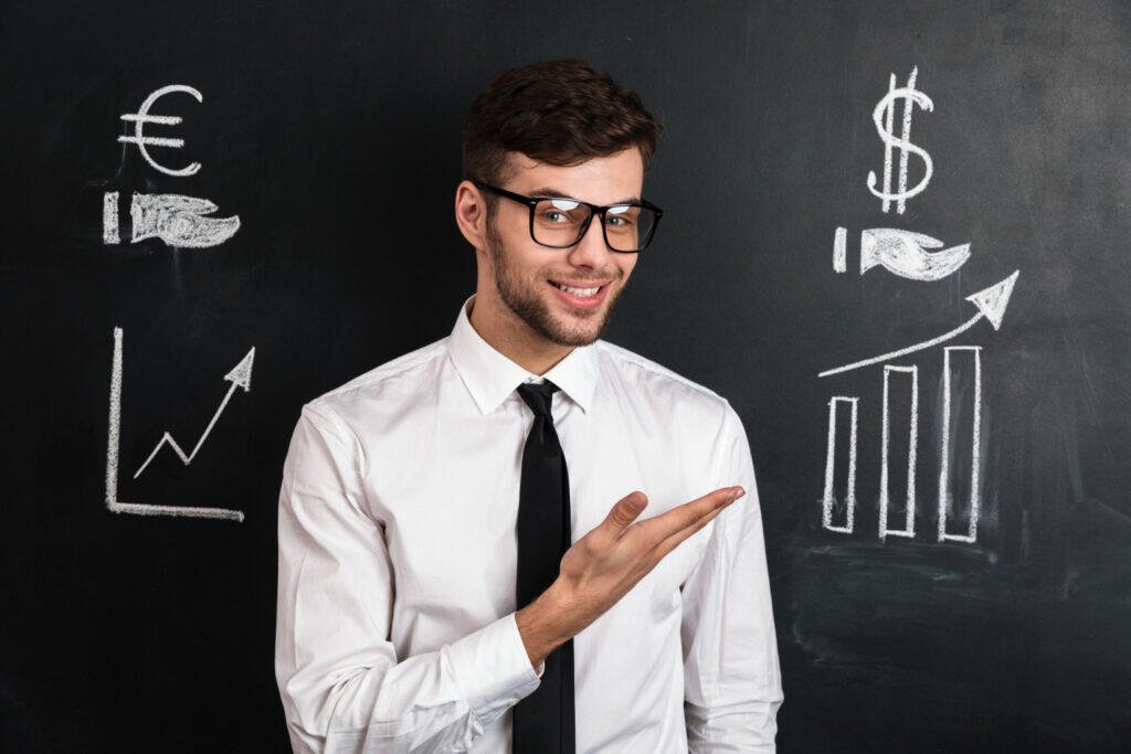 Smiling financial advisor gesturing towards growth charts on chalkboard. 1:1 financial coaching.
