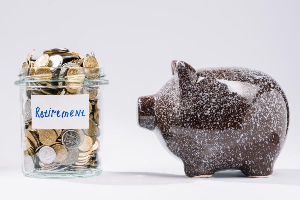 Glass jar filled with coins labeled "Retirement" next to a brown piggy bank. Adelaide retiree financial planning.