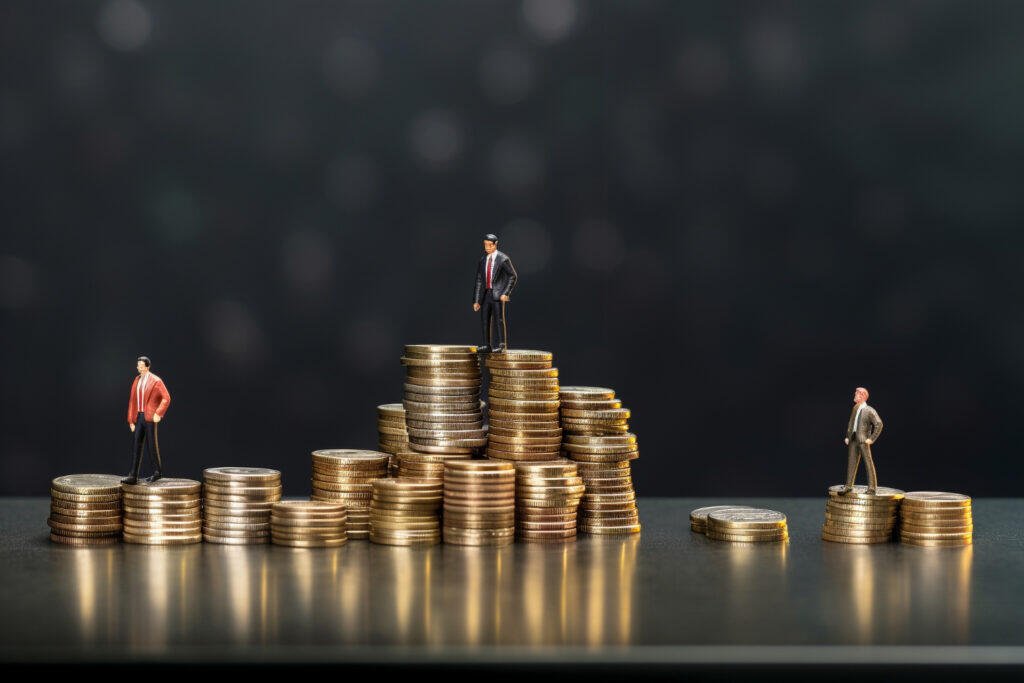 Miniature businessmen stand atop stacks of coins, illustrating cashflow and debt management.