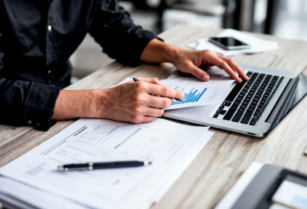 Person reviewing financial documents and graphs at a laptop. Financial planning in Adelaide.