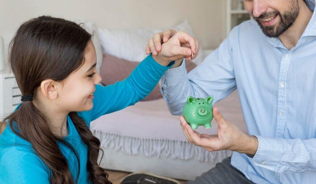 Father and daughter saving coins in piggy bank
