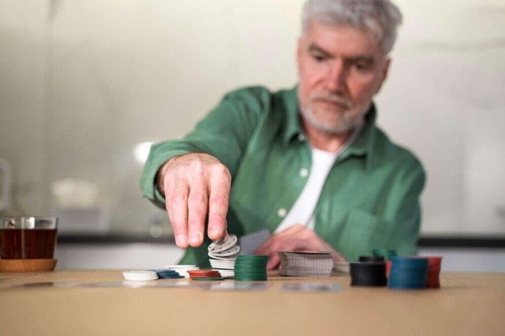 Senior man playing cards, managing his superannuation fund in retirement.