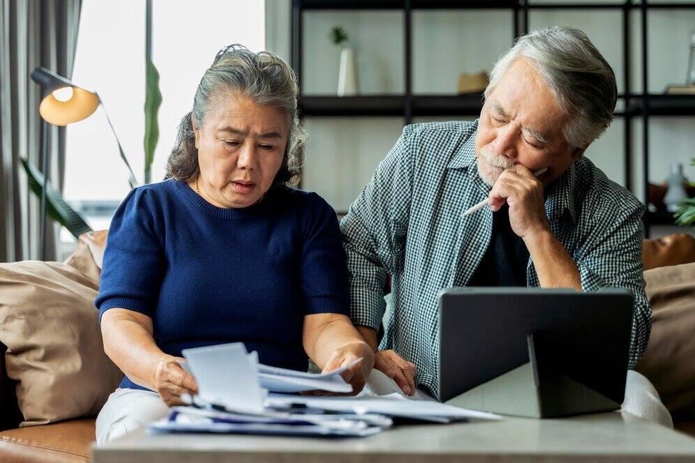 Senior couple reviewing retirement finances, considering rent vs. own options.